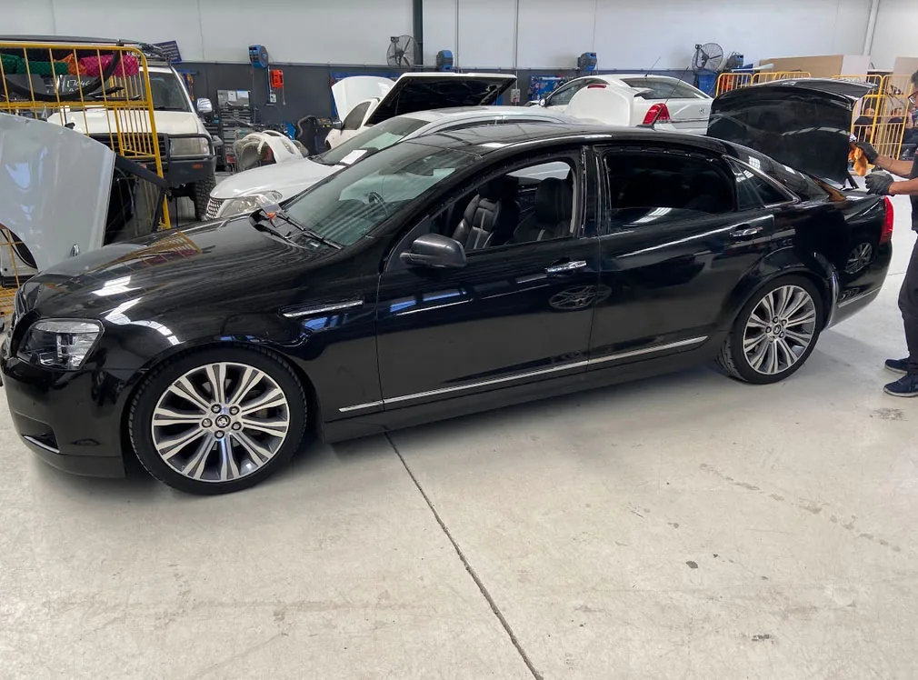 The same black sedan after full overspray removal, back to gloss